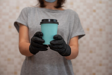 Naklejka premium A woman in gloves holds a turquoise craft glass