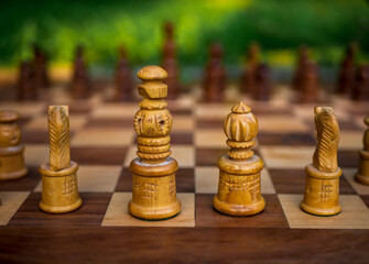 Wooden chess board with wooden pieces with sunlight. Selective focus on King and Queen.