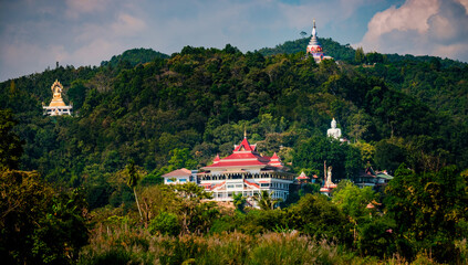 Fototapeta na wymiar Thai temple over a hill with traditional architecture, big white Buddha and golden Buddha and a pagoda on the top.