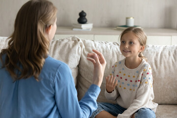 Female therapist teaching pretty kid girl to speak gestures language. Teacher and child practicing speaking, sign communication, vocal exercises, correct pronouncing, foreign language skills