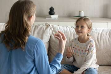 Female therapist teaching pretty kid girl to speak gestures language. Teacher and child practicing...