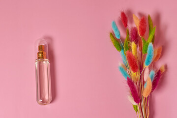 A glass transparent perfume bottle and a bouquet of dried lagurus flowers