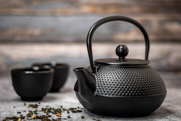 Black teapot with some green tea on the table