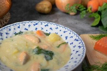 テーブルに置かれた鮭とほうれん草のクリームシチューとその材料のクローズアップ