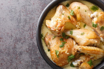 Shkmeruli is a traditional Caucasian Georgian dish of chicken in garlic sauce closeup in the pot on the table. Horizontal top view from above