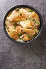 Shkmeruli Chicken cooked in milk and garlic is a favorite rustic Georgian dish often baked in a traditional clay pot closeup on the table. Vertical top view from above