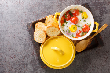 Eggs en Cocotte with cream and cheese served with warm toast for dipping closeup in the wooden tray...