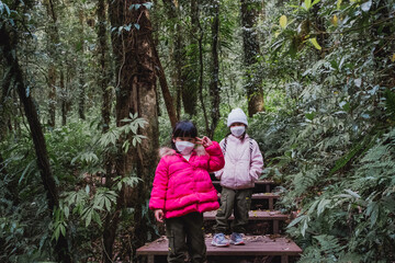 Fototapeta premium Children with backpacks hiking in nature with family. Two preschoolers in winter clothes explore the forest, play and learn in nature. a new normal lifestyle.