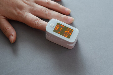 Oximeter on the index finger of a woman's hand with poor readings. Very low level of oxygen in the...