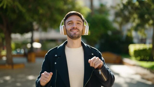 Young hispanic man smiling confident listening to music at park