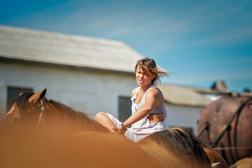 A young beautiful girl works on a horse farm.