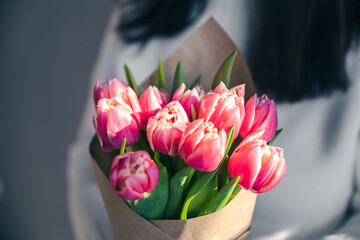 Close-up, a bouquet of pink tulips in female hands.