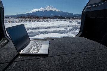 車中でのリモートワーク（ワーケーション）イメージ　積雪した富士山の麓で　remote working in the car at the foot of mount Fuji in winter