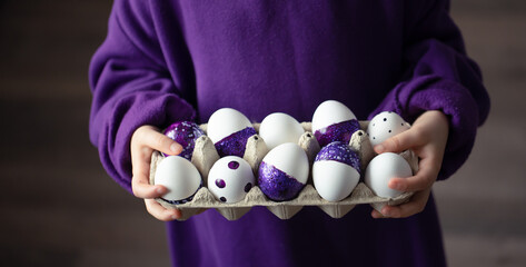 Close-up of a tray of purple Easter eggs in the hands of a child.