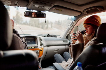 woman in a hat with a phone in her hands shoots a video of nature in a car