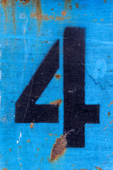 Number 4 in black paint on an old blue iron surface with rust texture and traces of dirt.