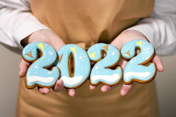 Pastry chef holds Christmas gingerbread in the form of 2022 numbers. New Year concept.