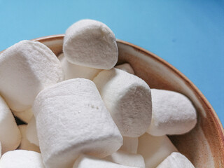 Close up of White fluffy marshmallows in bowl and blue background