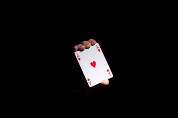 hands of illusionist showing play cards in the dark