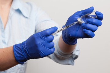 hands of a nurse in medical gloves dialing a vaccine or medicine for injection into the syringe