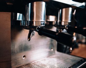 Details of a modern chrome coffee machine in the dim light of a coffee shop - professional barista...