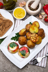 Portion of delicious chicken aspic and baked potato on a plate on concrete table