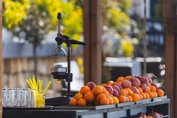 close-up of a manual metal juicer and a lot of fresh oranges on the store counter
