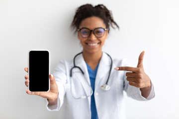 Doctor pointing at big white empty smartphone screen, mock-up