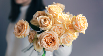 Close-up of orange roses in female hands.