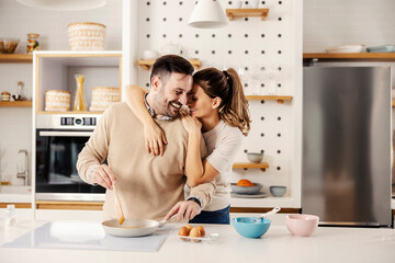 A happy couple making breakfast in the kitchen at their cozy home.