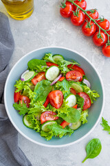 Salad with fresh vegetables and cheese in a bowl on a concrete background. Greek salad, vegetarian dish. Top view.