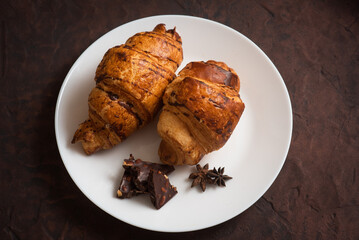 delicious, crispy croissants, chocolate on plate on dark table. Tasty food