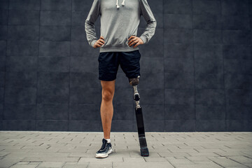A proud handicapped sportsman with artificial leg standing outdoors with hands on hips. Legs and...
