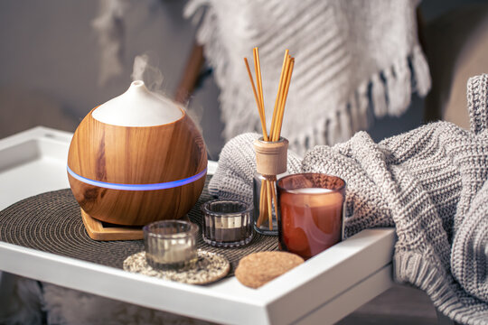 A cozy composition with an aroma diffuser and candles in a home interior.