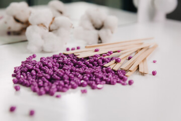 Close-up of purple wax granules scattered from a jar. Beauty procedure to remove unwanted hair from the body. - obrazy, fototapety, plakaty