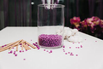 Close-up of purple wax granules scattered from a jar. Beauty procedure to remove unwanted hair from...