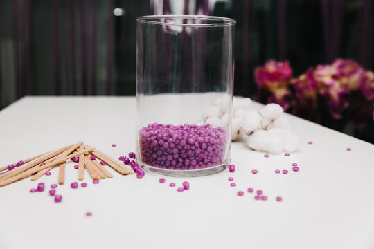 Close-up of purple wax granules scattered from a jar. Beauty procedure to remove unwanted hair from the body.