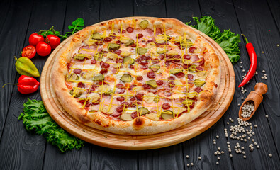 Delicious and fresh pizza with ham, sausage and pickled cucumbers