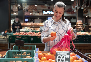 A young woman chooses fruits in a supermarket.