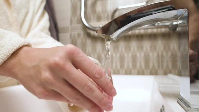 Women's hands in the bathroom washes a splint from bruxism. Preventive regular cleaning of the aligner to correct the bite and align the teeth