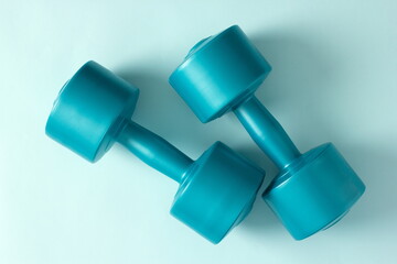 Blue vinyl dumbbells on a blue background. Close-up. Top view
