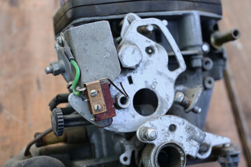 Close-up view of a gasoline carburetor. Repair of an old car in a workshop. Selective focus. Blurred background.