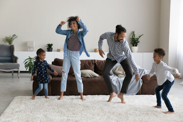 Overjoyed millennial African American couple parents making funny moves, dancing to energetic disco...
