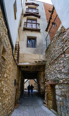 Fototapeta na wymiar Narrow alley with a passageway under the houses where people walk, Cuenca Spain.