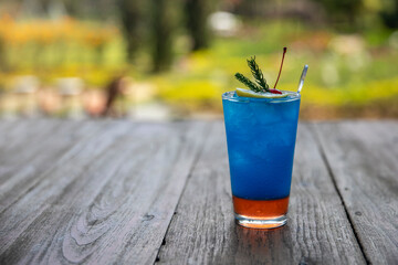 Close up glass of blue lagoon cocktail decorated with lime on nature background. Cold drinks and cocktails in summer.