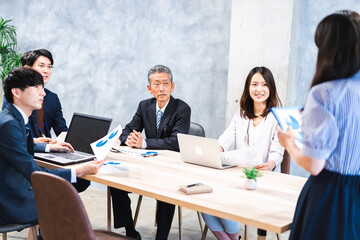 商品企画のプレゼンテーションを聞くビジネスパーソン