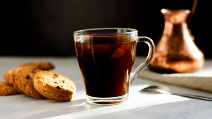Morning vibes. A cup of black coffee. Cookies with chocolate drops and turkish copper cezve s in the background.
