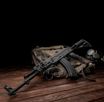 Soviet carbine in modern body kit. Weapons of Russia and the Soviet Union. Classic Soviet AK assault rifle and gas mask on a wooden back