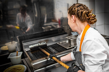 chef with metal brush clean the grill oven in kitchen