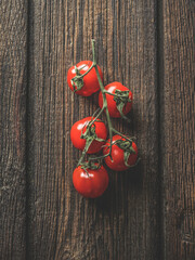 Close up of red tomatoes on dark rustic wooden background. Seasonal healthy summer vegetable.Top...